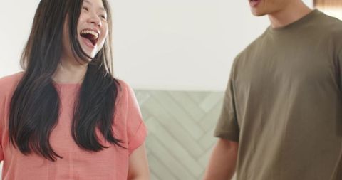 Young diverse couple laughing in bright modern kitchen with herringbone tile and warm tones