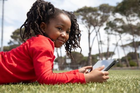 Young Girl Enjoying Digital Tablet Outdoors in Sunny Park