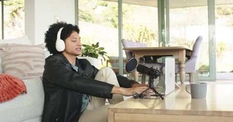 Recording podcast at home with usb microphone and headphones in sunlit living room