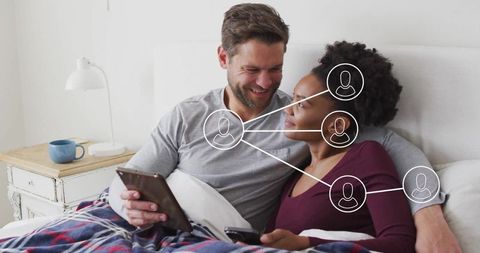 Couple Relaxing in Bed with Technology and Connecting App Concept