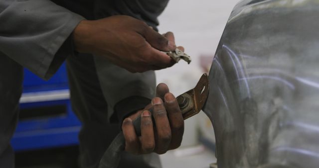 Hands of a mechanic actively working on a car chassis, demonstrating practical automotive repair skills. Useful for illustrating auto repair services, mechanical engineering education, vehicle maintenance tutorials, and showcasing the expertise required in the automotive repair industry.