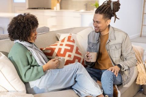 Couple Enjoying Cozy Coffee Conversation Sitting on Modern Living Room Sofa