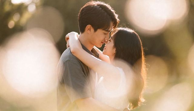 Romantic young couple embracing in golden-hour garden, intimate gaze, soft bokeh light