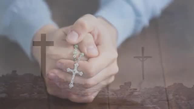 The scene shows hands clasping a rosary against a blurred background featuring cross silhouettes and a rocky terrain. These elements reflect themes of faith, devotion, and prayerful meditation. Useful for religious content, spiritual guidance materials, and meditation promotion imagery.