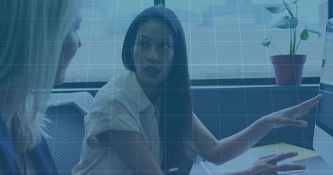 Female professional pointing at monitor during collaborative discussion in modern office