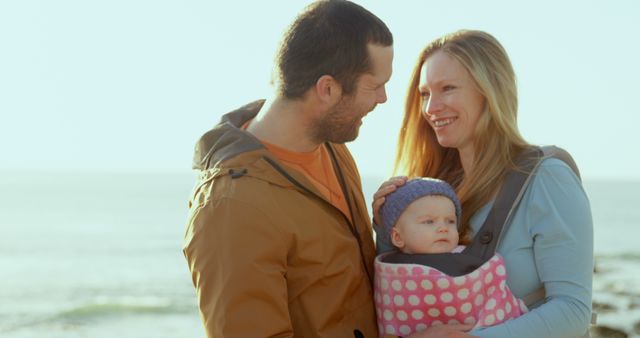 Smiling Parents Carrying Baby in Carrier on Beach - Download Free Stock Images Pikwizard.com