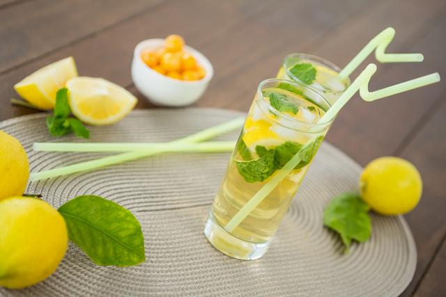 Glass of mojito cocktail, lemon and yellow cherries on the wooden board