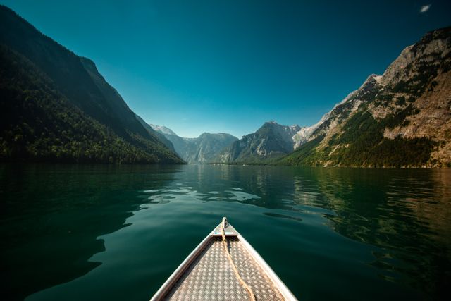 Foreground view from a boat moving towards breathtaking mountains on a calm lake under a clear blue sky. Perfect for promoting outdoor adventures, serene natural retreats, and ecotourism destinations. Great for travel blogs, nature-related advertisements, and peaceful getaway brochures.