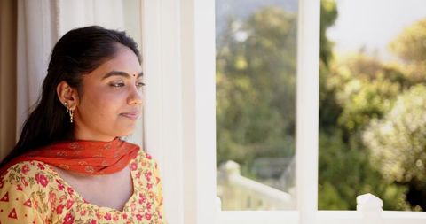 Smiling Indian Woman in Sari Enjoying Serene View by Window