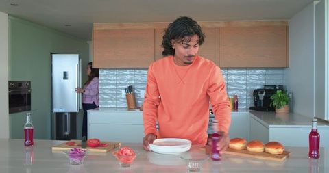 Young man and friend preparing casual brunch on modern kitchen island with drinks