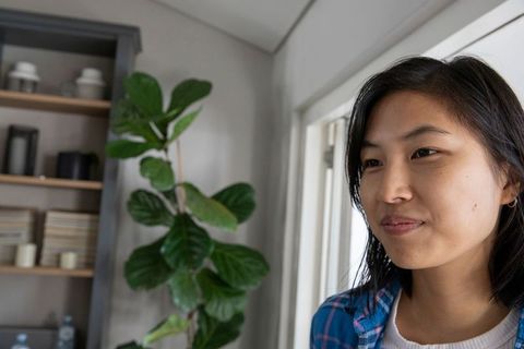 Asian Woman in Minimalist Home With Indoor Plant Background