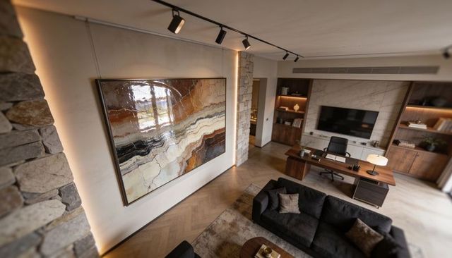 Glossy earth-tone abstract painting reflecting light in contemporary home office