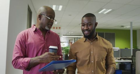 Two Happy African American Businessmen Walking and Talking in Office