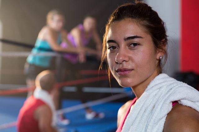 Close-up portrait of female athlete with towel against boxing ring