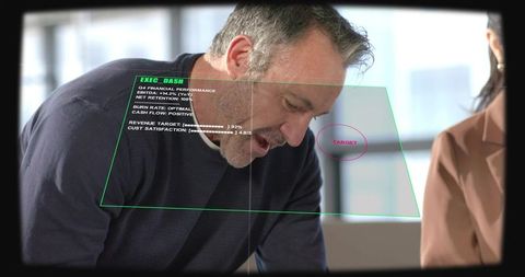 Mature executive leaning forward explaining augmented reality dashboard in boardroom