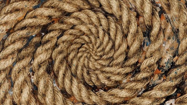 Coiled natural fiber rope on weathered metal background