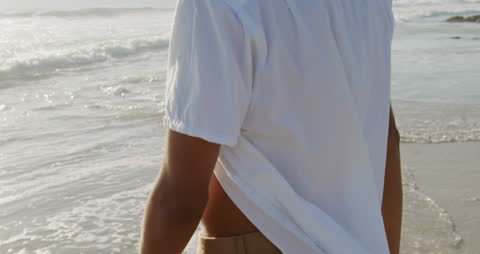 Young Man Relaxing by Ocean Waves on Sunny Beach Day
