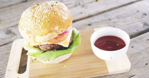 Sesame cheeseburger with melted cheese and ketchup on rustic cutting board, stars