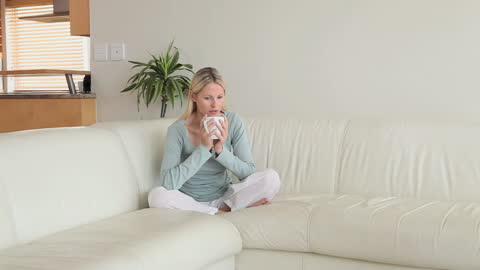 Woman Enjoying Coffee on Comfortable Couch Relaxing at Home