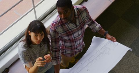 Diverse Team Discussing Blueprint in Modern Office