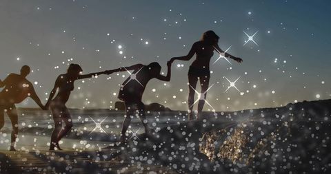 Women Helping Each Other Walk on Rocky Shoreline at Sunset with Sparkling Bokeh Overlay, Teamwork