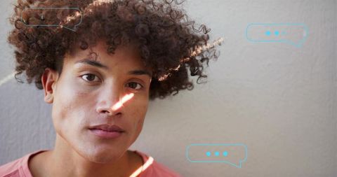 Contemplative young man leaning against wall with sun streak and speech bubble graphics