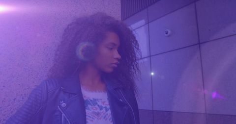 Fashionable woman in leather jacket standing in stylish modern interior