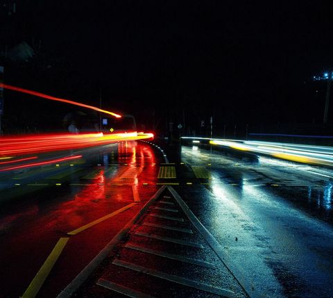 Dynamic night traffic with light trails on wet street