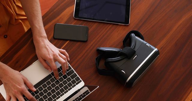 Person Using Laptop with Virtual Reality Headset and Digital Devices on Wooden Desk - Download Free Stock Images Pikwizard.com