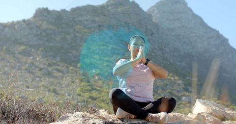 Woman meditating outdoors on rocks at mountain base