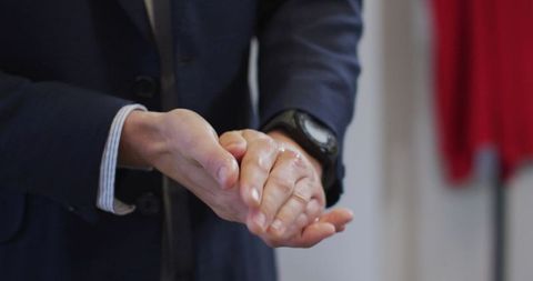 Businessman sanitizing hands for hygiene at office