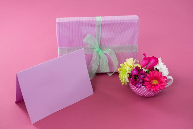Close-up of gift box with happy mother day tag and blank card against pink background