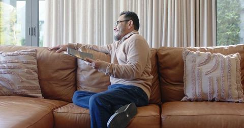Mature Man Relaxing on Sofa with Tablet in Bright Living Room