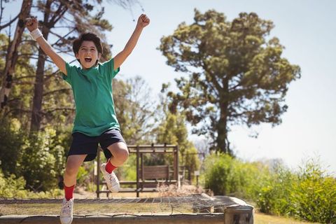 Energetic boy jumping on trampoline platform in sunny park