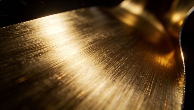 Brushed gold metal surface displaying macro texture, brushed grooves and curved rim