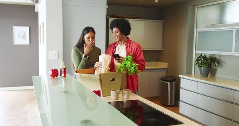 Couple unpacking groceries in modern kitchen with cardboard bag