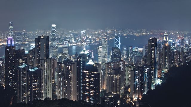 Featuring the breathtaking night skyline of Hong Kong, this image captures the brightly lit modern architecture and bustling urban life. Skyscrapers and high-rise buildings stand tall around the iconic Victoria Harbour, making it ideal for travel brochures, cityscape prints, and promotional material for tourism in Asia.