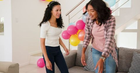 Women decorating house with balloons for festive birthday celebration
