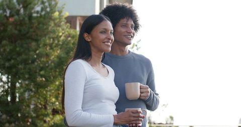 Diverse Couple Relaxing on Patio with Ceramic Mugs