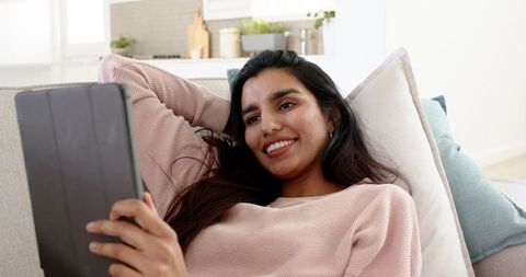 Woman Relaxing on Sofa with Tablet in Modern Living Room