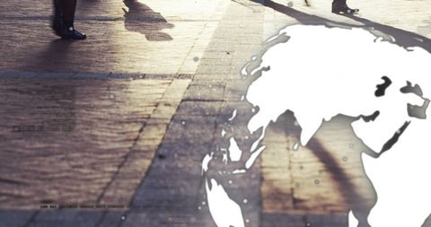 Commuters walking across sunlit plaza casting long shadows with world map overlay