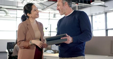 Diverse professionals collaborating and reviewing tablet in modern open-plan office