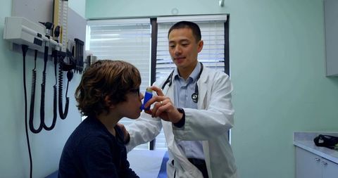 Doctor Demonstrating Inhaler Spacer to Child During Pediatric Examination for Asthma Care