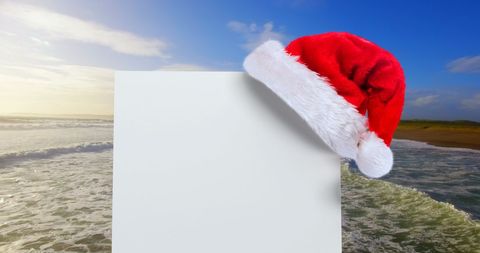 Santa Hat Adorning Blank Card Beside Oceanic Horizon