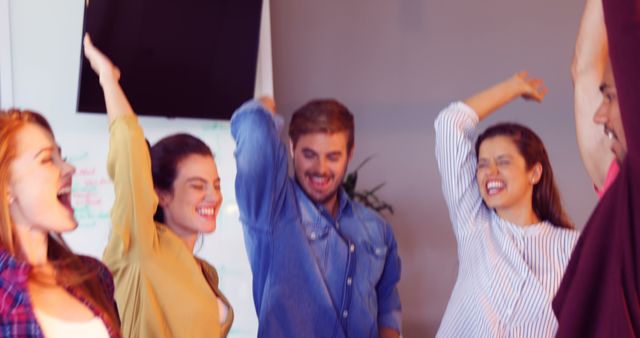 Group of colleagues expressing excitement and joy in a modern office setting. Perfect for representing teamwork, business success, corporate celebrations, and enthusiastic professional environments. Suitable for business websites, corporate promotions, and marketing materials.