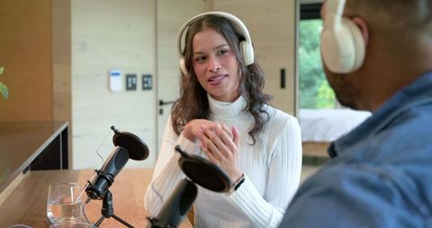 Co-hosting podcast in modern home studio recording candid conversation between woman and african ame