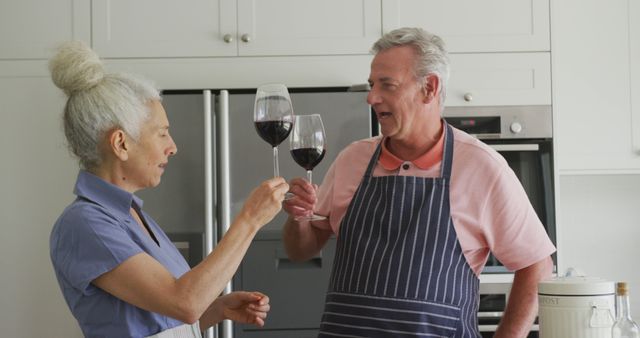 Elderly couple enjoying wine together in kitchen - Download Free Stock Images Pikwizard.com