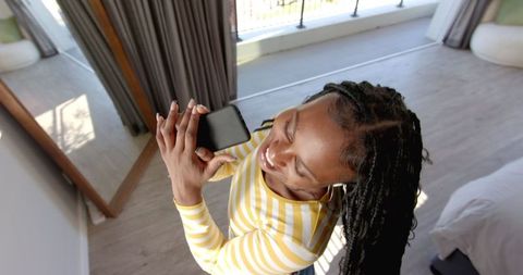Joyful woman with dreadlocks taking selfie indoors