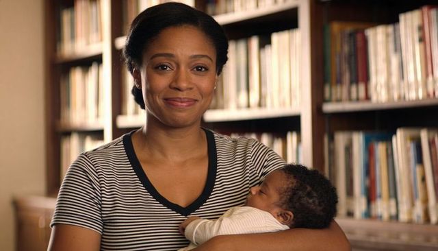 African american mother cradling sleeping newborn in library, warm parenting portrait