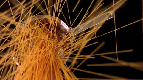 Spaghetti Falling into Pot Against Black Background in Slow Motion